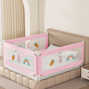 Pink baby bed rail with cartoon designs on a bed in a room.
